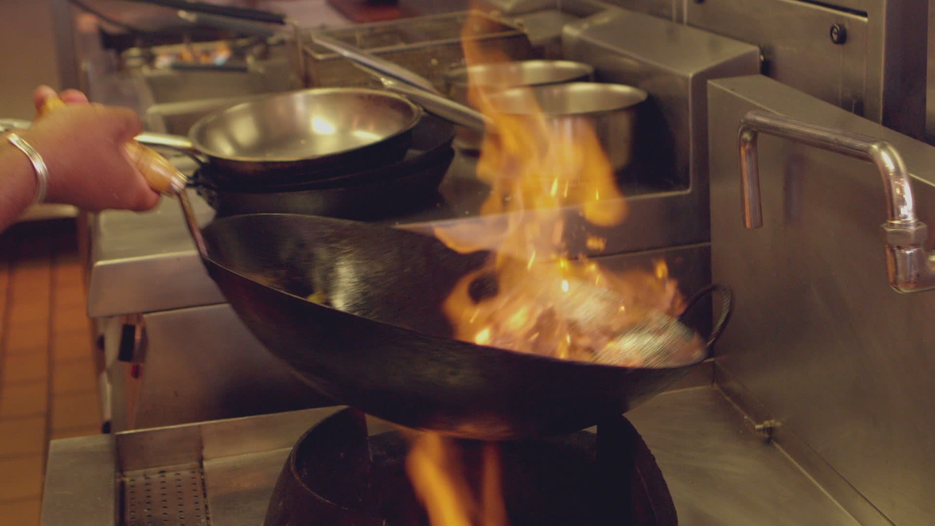 Chef cooking with flames in a wok